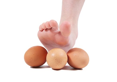 Foot crushing eggs on white background
