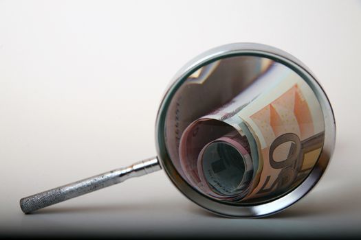 Money under magnifying glass on white background