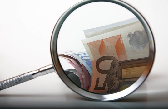 Money under magnifying glass on white background