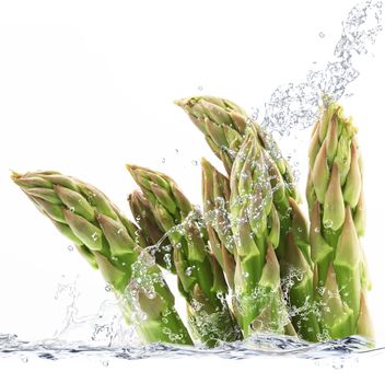 Fresh asparagus falling in pure water