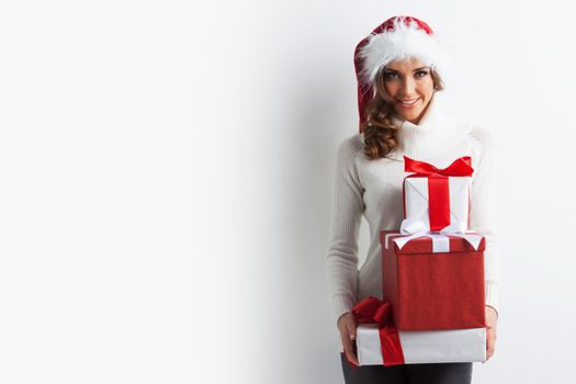 Happy woman in Santa hat with stack of Christmas gifts