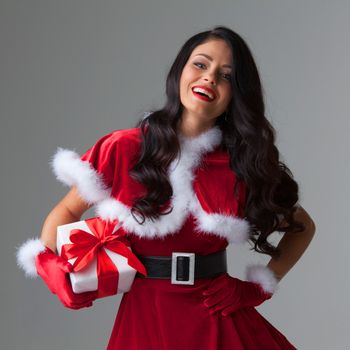 Woman in red Santa Claus outfit holding christmas gift box