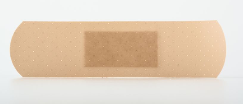 Close-up on a sticky beige plaster to protect wound, isolated on white
