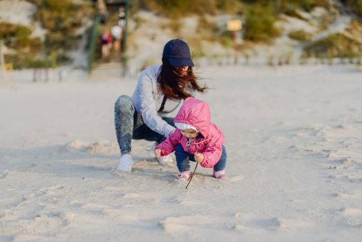 Mother and little daughter having fun on the beach. Authentic lifestyle image.