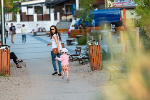 Mother and little daughter having fun on the beach. Authentic lifestyle image.