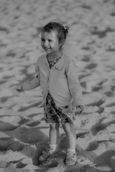 Adorable toddler girl on a sunny sand beach. Authentic lifestyle childhood image
