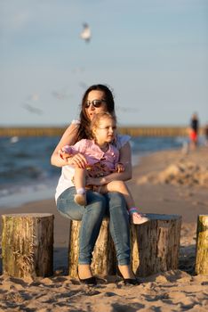 Mother and little daughter having fun on the beach. Authentic lifestyle image.