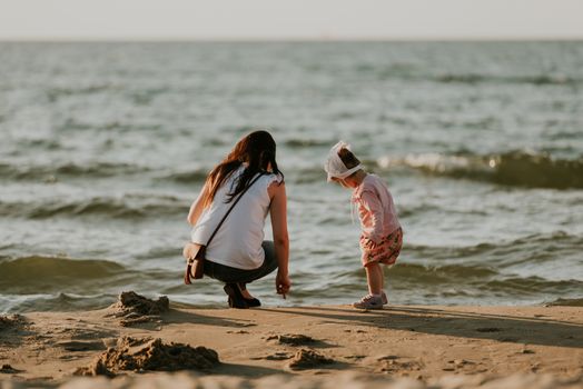 Mother and little daughter having fun on the beach. Authentic lifestyle image.