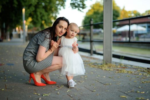 Happy mother and daughter in the park. Beauty nature scene with family outdoor lifestyle. Happy family resting together on the green grass, authentic lifestyle image
