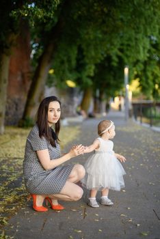Happy mother and daughter in the park. Beauty nature scene with family outdoor lifestyle. Happy family resting together on the green grass, authentic lifestyle image