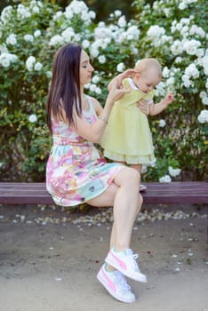 Happy mother and daughter in the park. Beauty nature scene with family outdoor lifestyle. Happy family resting together on the green grass, authentic lifestyle image