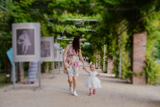 Happy mother and daughter in the park. Beauty nature scene with family outdoor lifestyle. Happy family resting together on the green grass, authentic lifestyle image