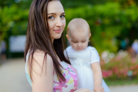 Happy mother and daughter in the park. Beauty nature scene with family outdoor lifestyle. Happy family resting together on the green grass, authentic lifestyle image