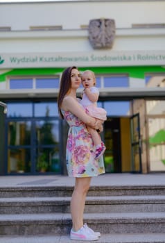 Happy mother and daughter in the park. Beauty nature scene with family outdoor lifestyle. Happy family resting together on the green grass, authentic lifestyle image