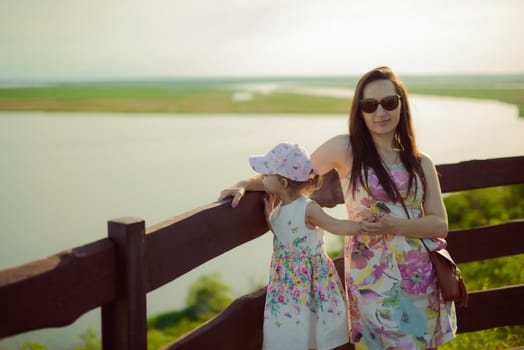 Happy mother and daughter in the park. Beauty nature scene with family outdoor lifestyle. Happy family resting together on the green grass, authentic lifestyle image