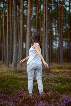 Woman in the forest where the purple heather blooms. copy space. Authentic lifestyle image