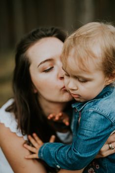 Happy mother and daughter in the park. Beauty nature scene with family outdoor lifestyle. Happy family resting together on the green grass, authentic lifestyle image