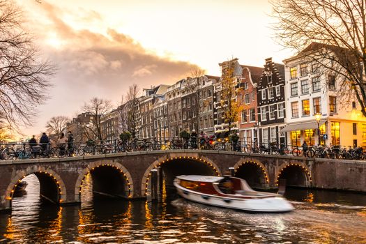 Amstedam, capital of Netherlands. Beautiful tranquil scene of city of Amsterdam at dusk. Bicycles along the street and on the bridge over the canal.