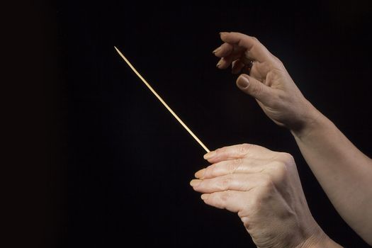 Female hands of an orchestra conductor on a black background