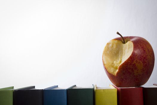 Apple and books on a white wall background
