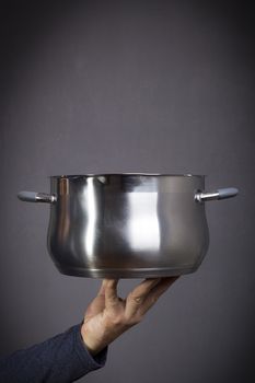 Metal pan in male hands on a black background