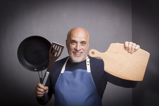 Gray-haired man with kitchen equipment on gray background