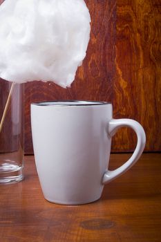 Cotton candy and cup with cocoa on a wooden table