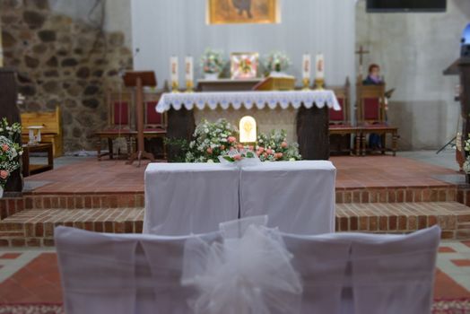 Church sanctuary before a wedding ceremony. Empty chairs for bride and groom