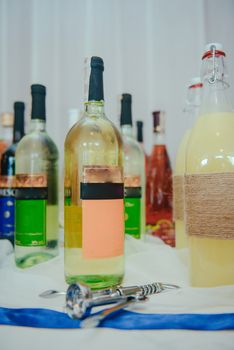 Bottle of cold vodka and wine bottle in bucket with ice and orange juice in jug on table, copy space. Alcohol bottles in ice bucket in restaurant. Wedding party