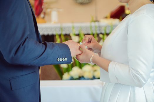 the bride and groom during the wedding ceremony put wedding rings on their fingers.