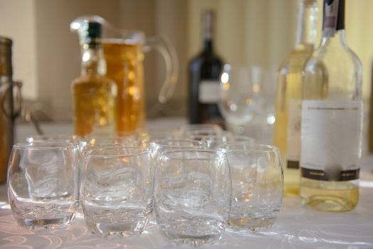 Bottle of cold vodka and wine bottle in bucket with ice and orange juice in jug on table, copy space. Alcohol bottles in ice bucket in restaurant. Wedding party