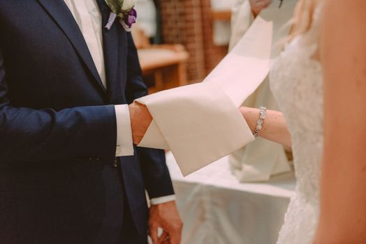 the bride and groom during the wedding ceremony put wedding rings on their fingers.