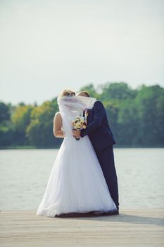 Bride and groom at a photo session in the nature. Lake and pier.