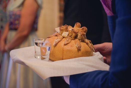Traditional polish greeting the bride and groom by the parents with bread and salt. Vodka also in glasses.