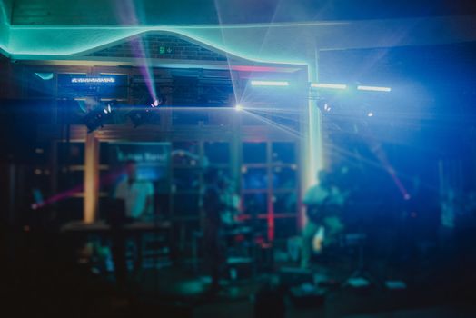 DJ plays music at wedding party. Colorful light rays.