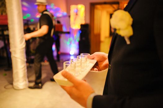 Bottle of cold vodka and wine bottle in bucket with ice and orange juice in jug on table, copy space. Alcohol bottles in ice bucket in restaurant. Wedding party
