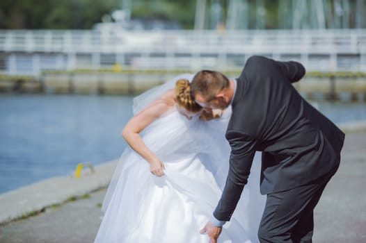 Bride and groom at a photo session in the nature. Lake and pier.