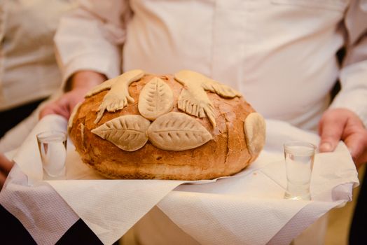 Traditional polish greeting the bride and groom by the parents with bread and salt. Vodka also in glasses.
