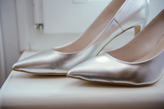 The bride shows white wedding shoes. Wedding detail. Close up