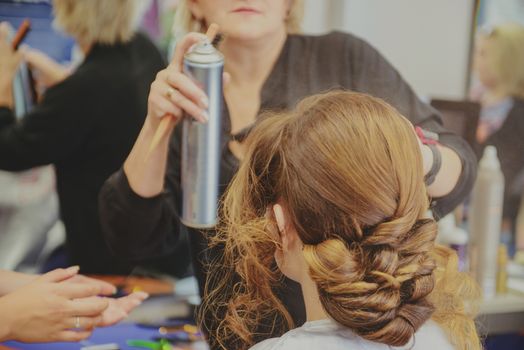Young beautiful bride applying wedding make-up by professional make-up artist.