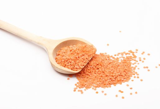 orange lentils on wooden spoon on white background