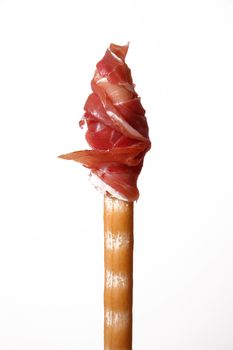 Slice of raw ham rolled up on a breadstick