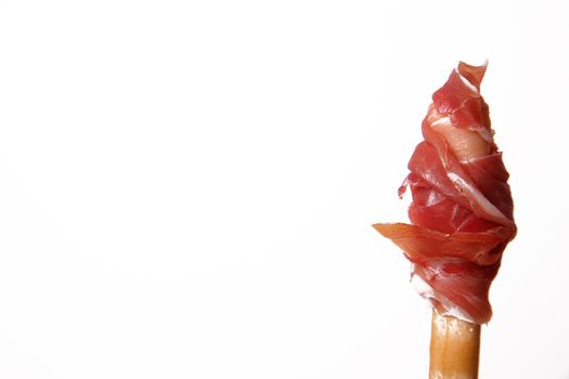Slice of raw ham rolled up on a breadstick