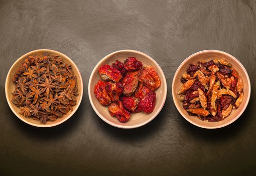 bowls with anise star and dry pepper on dark background