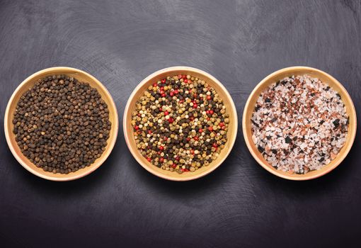 bowls with salt and pepper on dark background