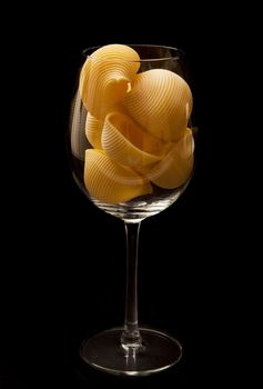 italian pasta in to glass on black background