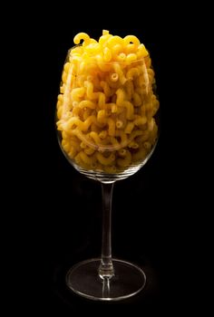 italian pasta in to glass on black background