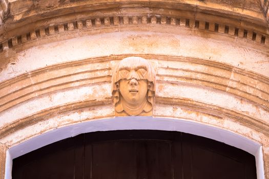 Gothic detail. Young woman portrait at the entrance of a 200 years old building in Ciutadella town, Menorca (Spain)