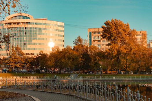 City ponds in the autumn. Trees covered with yellow and orange leaves are reflected in the water. Blue sky.