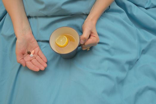 Woman hands taking medicines in bed